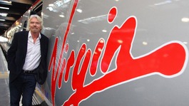 Richard Branson leaning against a Virgin Train.