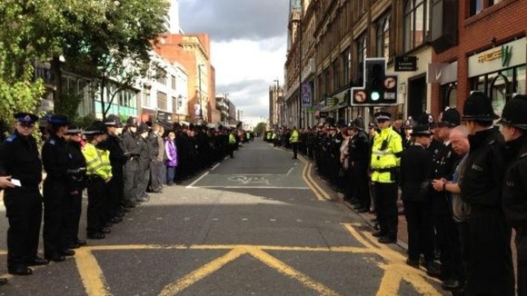 Members of the public stand beside police officers in Deansgate Street in Manchester