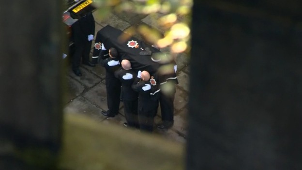 Officer carry the coffin following the funeral procession through Manchester