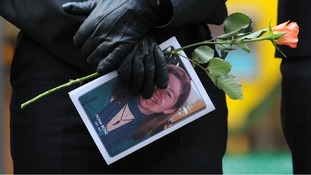 A police officer holds a rose and an Order of Service as officers line the route along Deansgate