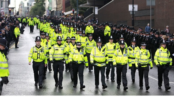 Police officers march along Deansgate as they make their way to Manchester Cathedral