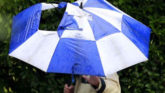 A man with a broken umbrella walks through Stockport, where commuters were hit by the weather last week.