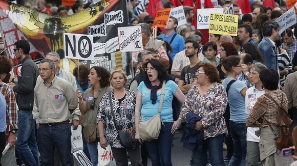 Demonstrators march with banners during a protest against public health and education cuts in Madrid.