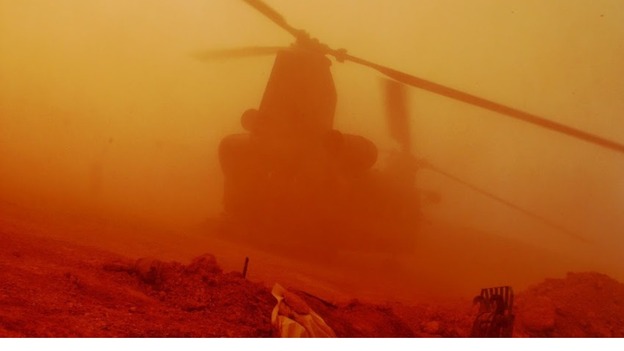 An RAF Chinook kicking up dust as it lands. 