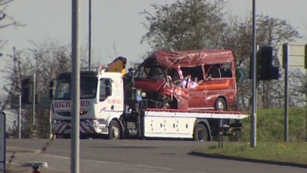 The crushed minibus getting towed away this morning