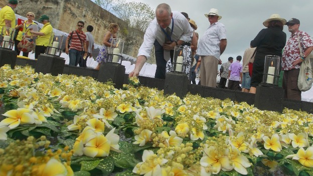 A man lays a flower at a pond commemorating the victims of the 2002 attacks
