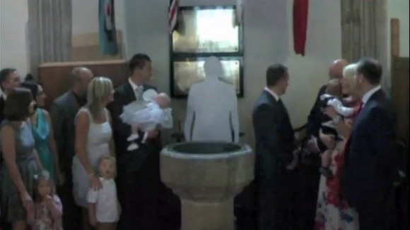 A congregation in church looking at a cardboard cut-out of a clergyman.