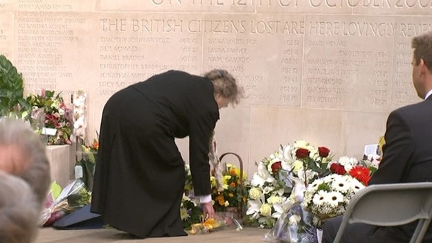 A woman lays a wreath of flowers by the memorial in St James's Park.