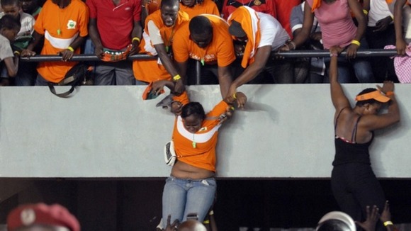 Fans of Ivory Coast's national football team help other fans escape the violence in the Leopold Sedar Senghor stadium in Dakar.