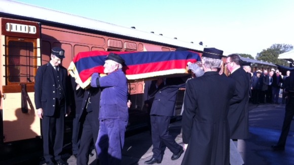 Rail engineers carry the coffin onto the train