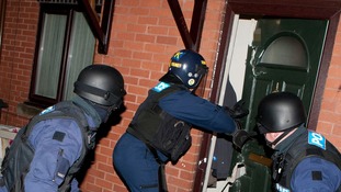 Police officers smash into a North Manchester property during drugs raids.