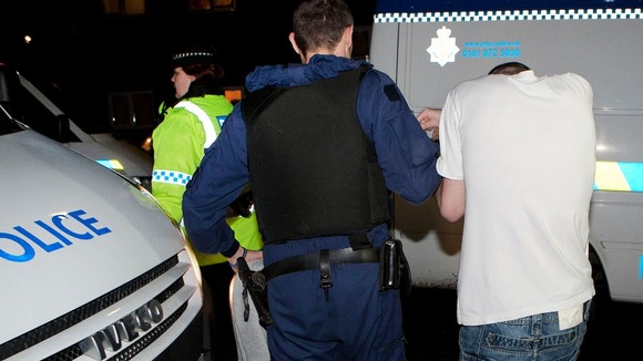 Police lead man away during dawn raids.