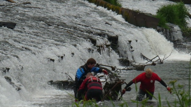 Workers clearing trolleys from river