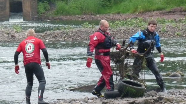 Workers clearing trolleys from river