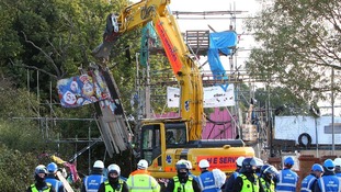 A mechanical vehicle begins to demolish the scaffolding tower at the main entrance to the Dale Farm travellers site near Basildon, Essex.
