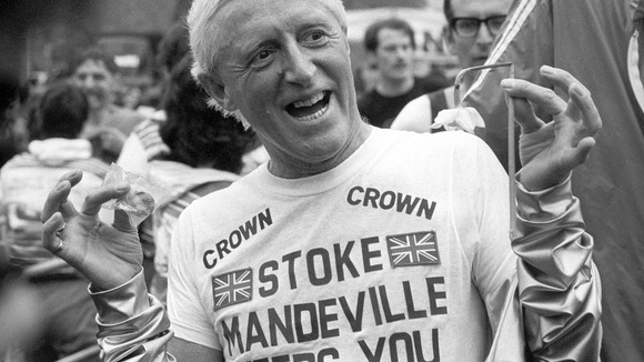 Television personality and charity fundraiser Jimmy Savile holds up a Daffodil and a medal after finishing the Marathon.
