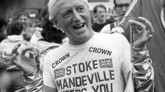 Television personality and charity fundraiser Jimmy Savile holds up a Daffodil and a medal after finishing the Marathon.