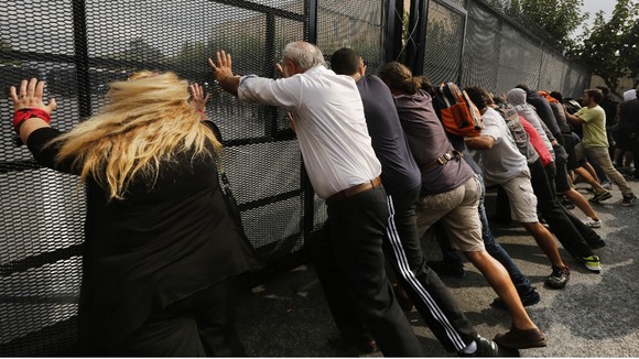 Greek protester push a police barricade outside the parliament during a violent protest against the visit of Angela Merkel this month