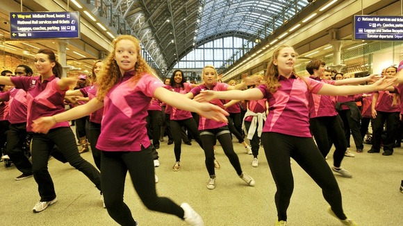 A group of Olympic Volunteers dancing.