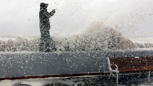 A man takes a picture while a wave crashes over the boardwalk in Ocean City