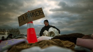A victim of hurricane Sandy takes blankets from a aid distribution site in the Staten Island