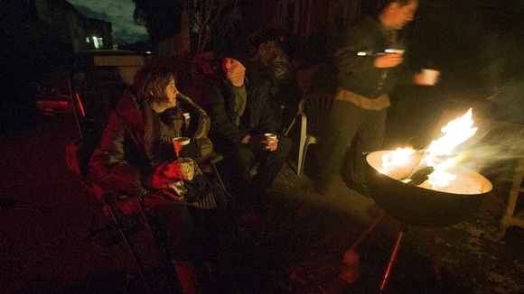 Victims of hurricane Sandy sit near a fire to stay warm outside their destroyed homes in Staten Island