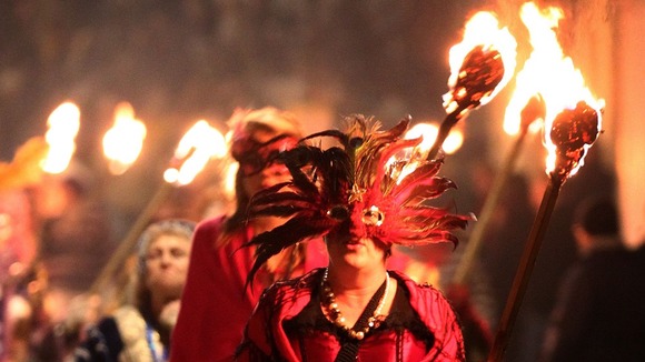 A woman in a feathered mask walks through Lewes town centre