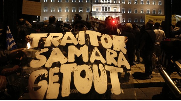 A protester holds a banner reading "Traitor Samara get out"(Greece's Prime Minister Antonis Samaras )in front of the parliament .
