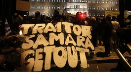 A protester holds a banner reading "Traitor Samara get out"(Greece's Prime Minister Antonis Samaras )in front of the parliament .