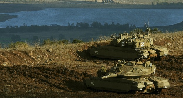 Israeli tanks stand in position overlooking a Syrian village from the Israeli occupied Golan Heights
