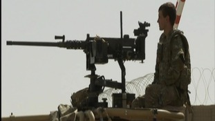 Soldier standing on watch on top of an armoured vehicle
