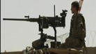 Soldier standing on watch on top of an armoured vehicle
