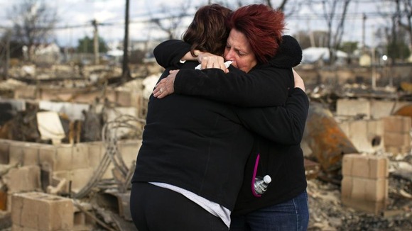 Neighbours Lucille Dwyer and Linda Strong embrace after looking through the wreckage of their homes