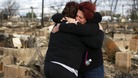 Neighbours Lucille Dwyer and Linda Strong embrace after looking through the wreckage of their homes