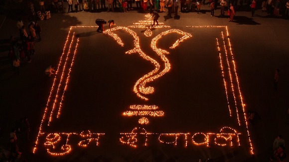 People light lamps to form the shape of Hindu god Ganesh in Chandigarh, northern India