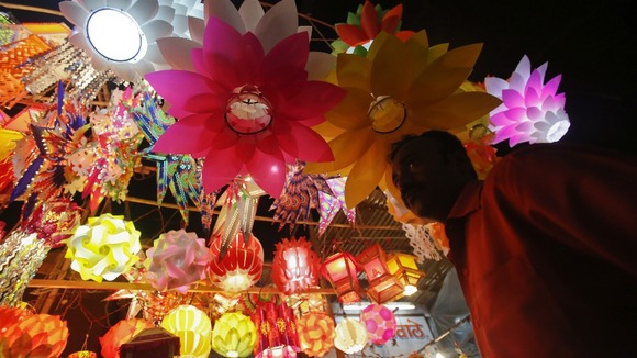 A man stands under lanterns for sale at a market in Mumbai on the eve of Diwali