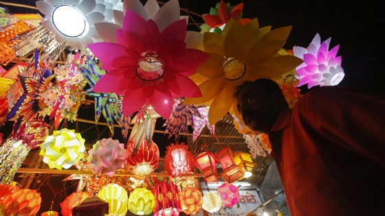 A man stands under lanterns for sale at a market in Mumbai on the eve of Diwali