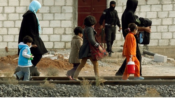 People from the northern Syrian town of Ras al-Ain walk along a train track as they attempt to cross into Turkey.