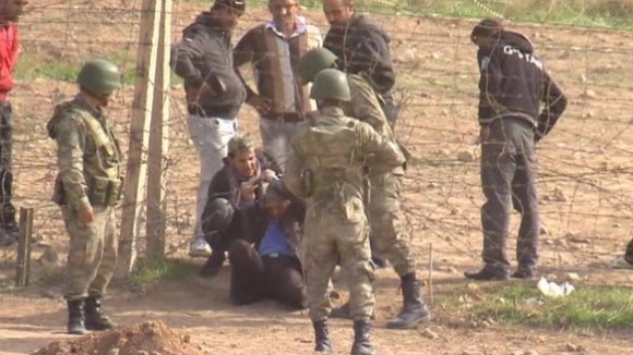 Men climb through the wires fence from Syria into Turkey.