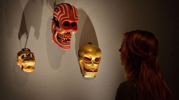 A visitor looks at masks which make up part of the collection