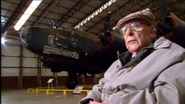 John Evans sat in an aircraft hangar with halifax plane in the background