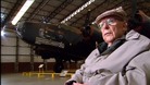 John Evans sat in an aircraft hangar with halifax plane in the background