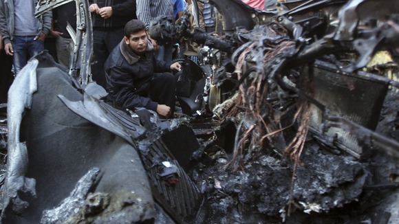 A policeman checks the destroyed car of Hamas's military chief following an Israeli air strike in Gaza City