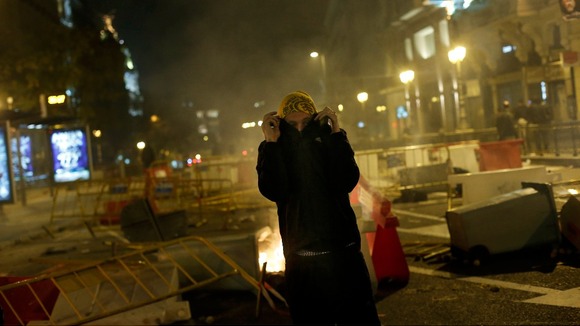 A protester stands next to a burning garbage container during a 24-hour nationwide general strike in central Madrid