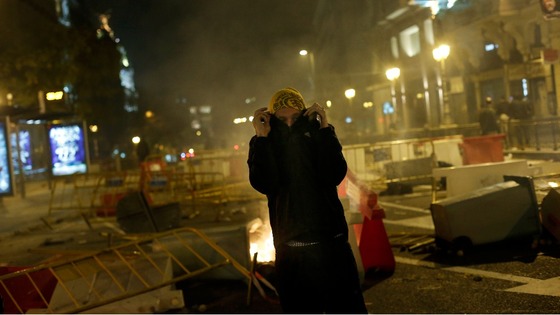 A protester stands next to a burning garbage container during a 24-hour nationwide general strike in central Madrid