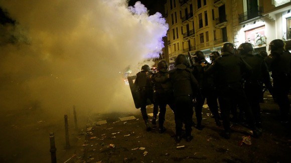 Spanish police officers advance through the smoke from a flare during a 24-hour nationwide general strike in central Madrid 