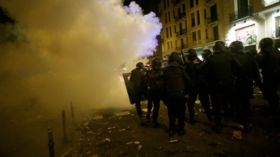 Spanish police officers advance through the smoke from a flare during a 24-hour nationwide general strike in central Madrid 