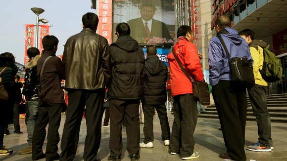 People watch a screen showing newly-elected General Secretary of the Central Committee of the Communist Party of China Xi Jinping