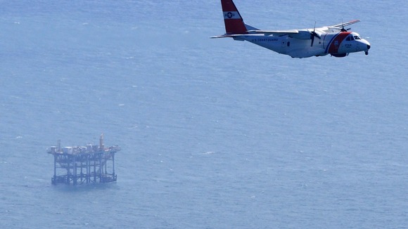 Plane from U.S. Coast Guard flies near an oil platform