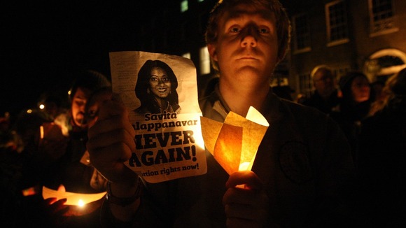 A protester holds a candle and poster with Savita Halappanavar's face on it